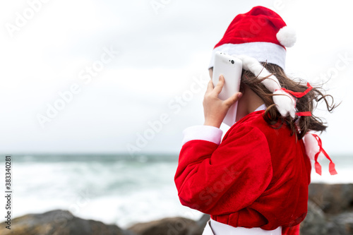 little girl in santa suit on the beach