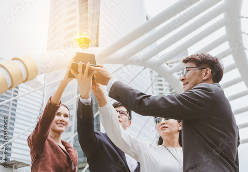 The best team helped each other reach their goals target to success. The hand of a business man and business women pick up the trophy and celebrate together. Asian Teamwork of successful concept