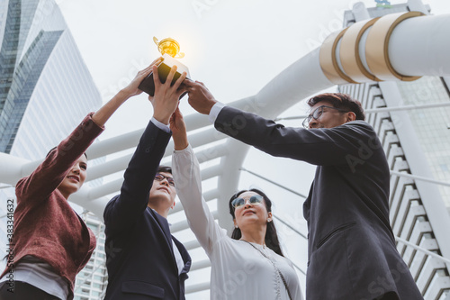 The best team helped each other reach their goals target to success. The hand of a business man and business women pick up the trophy and celebrate together. Asian Teamwork of successful concept