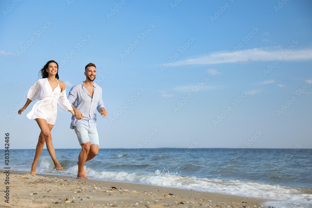Happy young couple running together on beach Happy young couple running together on beach