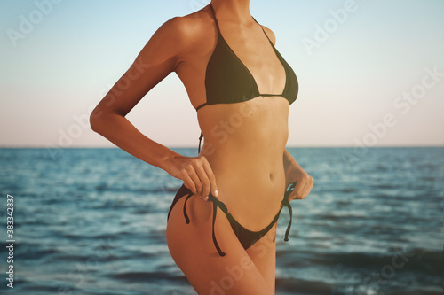 Woman in black stylish bikini on beach, closeup