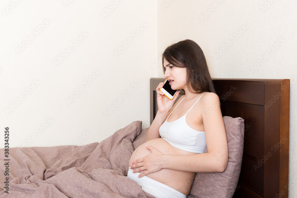 Emotional pregnant woman talking by mobile phone at home in bed Emotional pregnant woman talking by mobile phone at home in bed