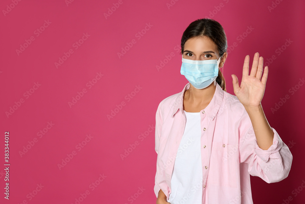 Woman in protective mask showing hello gesture on pink background, space for text. Keeping social distance during coronavirus pandemic Woman in protective mask showing hello gesture on pink background, space for text. Keeping social distance during coronavirus pandemic