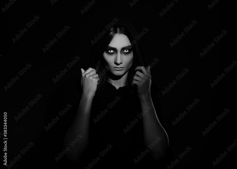 Mysterious witch with spooky eyes on dark background. Black and white effect Mysterious witch with spooky eyes on dark background. Black and white effect