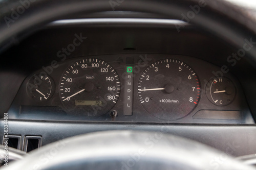 Car dashboard with white instrument circles with backlit arrows at night with a speedometer, tachometer with a mechanical gearshift gearbox to monitor the condition of the car on a black background.
