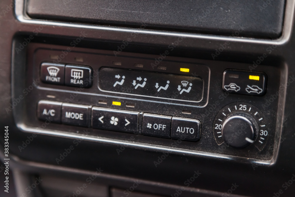 Close-up of the center console on a gray panel inside the car, with climate control and a red emergency button. Setting up and refueling the air conditioner in the workshop.