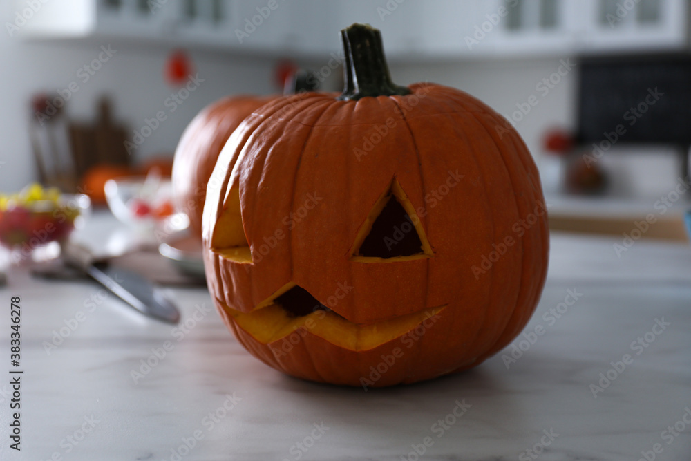 Pumpkin jack o'lantern on white marble table in kitchen. Halloween celebration Pumpkin jack o'lantern on white marble table in kitchen. Halloween celebration
