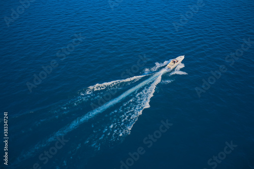 Yacht in the rays of the sun on blue water.  Aerial view luxury motor boat. Drone view of a boat sailing. Travel - image. Large speed boat moving at high speed side view.