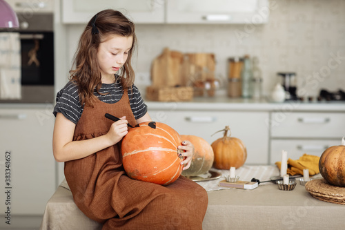 little girl paints a pumpkin for Halloween. preparation for halloween. Halloween holiday and family lifestyle background. selective focus