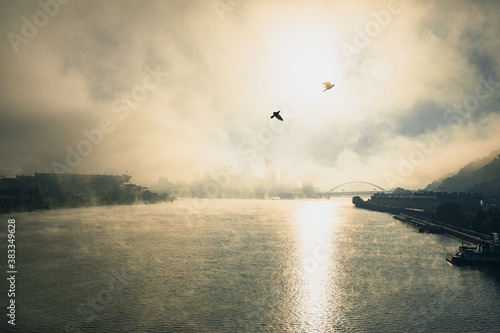 A foggy, misty morning over the Pittsburgh Ohio river with bridges and urban buildings and infrastructure.