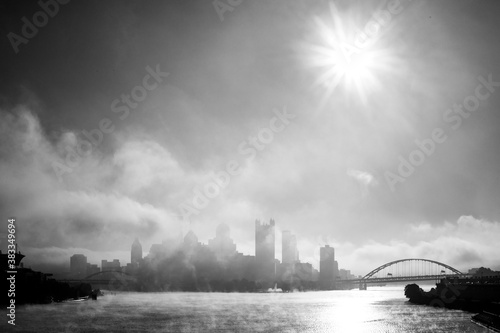 A foggy, misty morning over the Pittsburgh Ohio river with bridges and urban buildings and infrastructure.