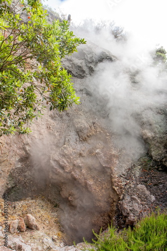 landscape with steamed air coming from volcanic hot springs and fumaroles