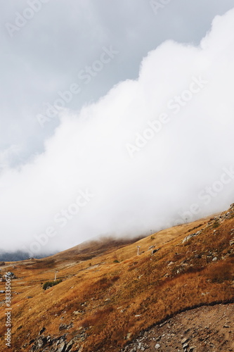 Cloudy day in mountains, clouds descend from the mountains to the village from above