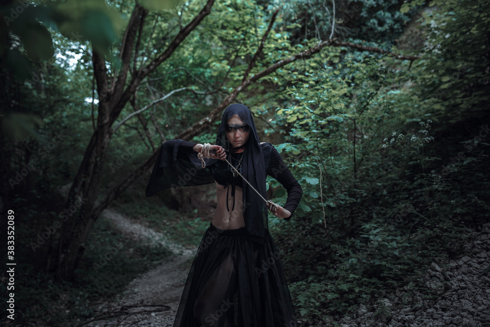 Mysterious sorceress woman witch beautiful black dress walk in gothic forest tree