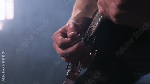 Close up hand of man playing electric guitar on stage. rock star professionally performs his solo part at rock concert or jazz festival.