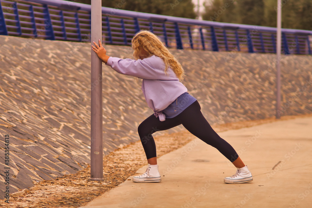 Young blonde woman doing stretching to start running.
