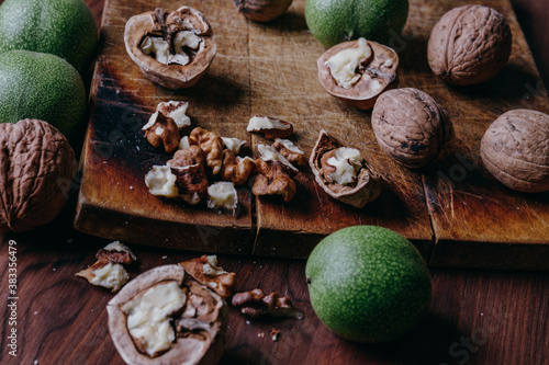 Fototapeta Naklejka Na Ścianę i Meble -  Walnut kernels, whole walnuts and green walnuts on rustic old wooden table.