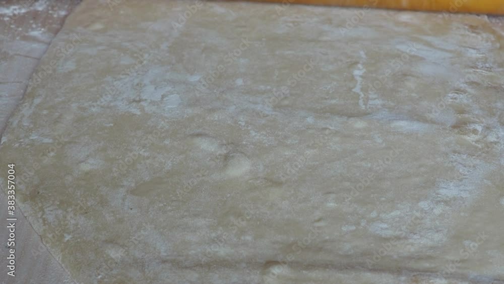 Close up woman hands rolls out dough using rolling pin cooking pizzeria. Baker rolling pizza dough on table before baking. Male hands rolling dough on wooden table Close up woman hands rolls out dough using rolling pin cooking pizzeria. Baker rolling pizza dough on table before baking. Male hands rolling dough on wooden table