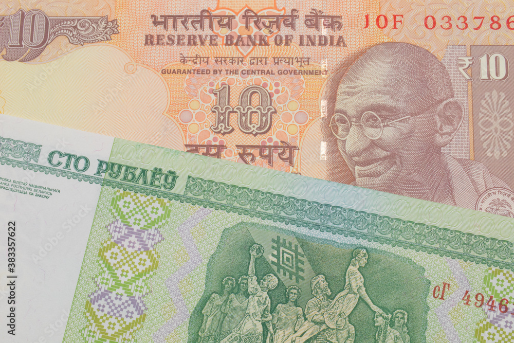 Fototapeta premium A macro image of a orange ten rupee bill from India paired up with a green one hundred ruble note from Belarus. Shot close up in macro.