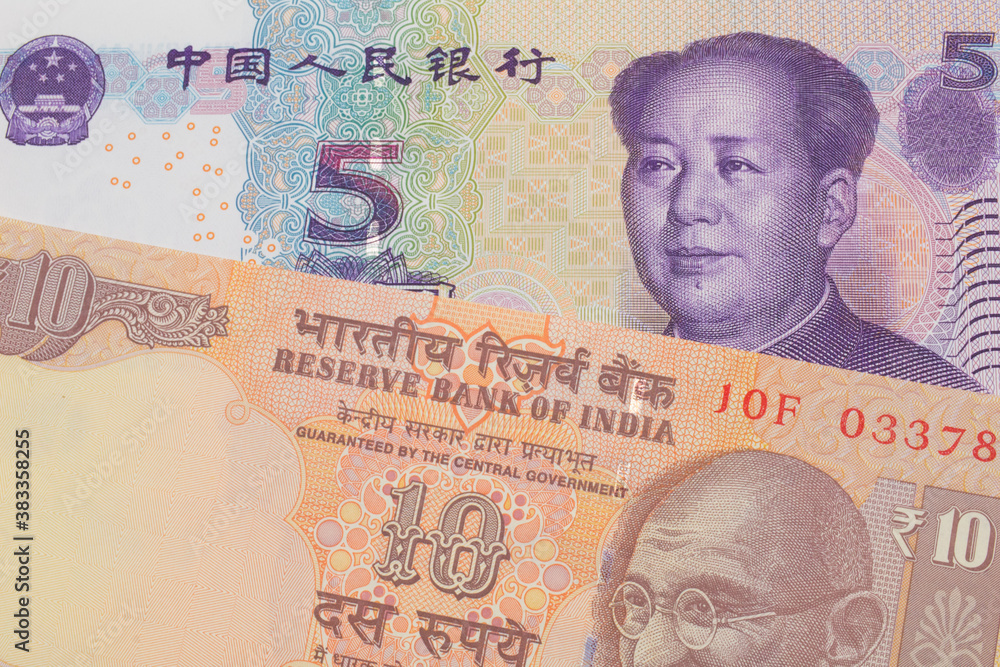 Fototapeta premium A macro image of a orange ten rupee bill from India paired up with a purple, blue and white five yuan bank note from China. Shot close up in macro.
