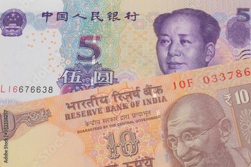 A macro image of a orange ten rupee bill from India paired up with a purple, blue and white five yuan bank note from China. Shot close up in macro.