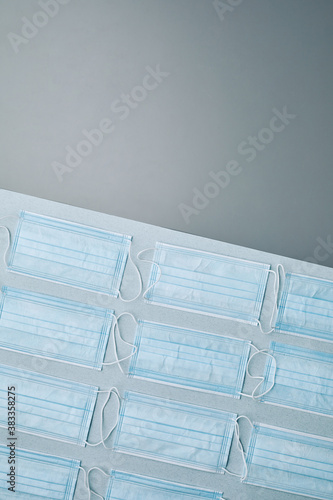 Flat lay composition of medical masks laid out in pattern over grey background, copy space above