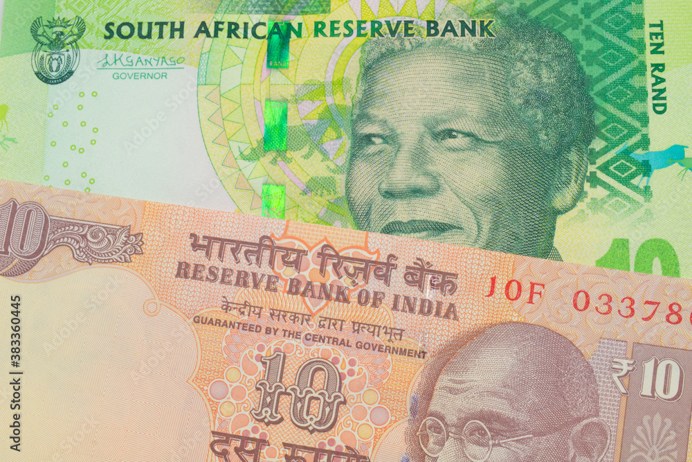 Fototapeta premium A macro image of a orange ten rupee bill from India paired up with a shiny, green 10 rand bill from South Africa. Shot close up in macro.