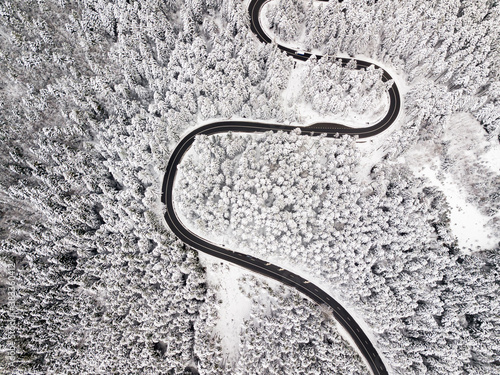 Aerial view of a road winding through snow covered forest