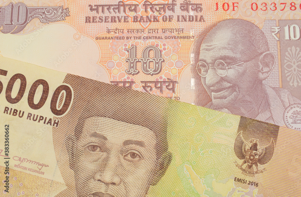 Fototapeta premium A macro image of a orange ten rupee bill from India paired up with a orange five thousand Indonesian rupiah note. Shot close up in macro.