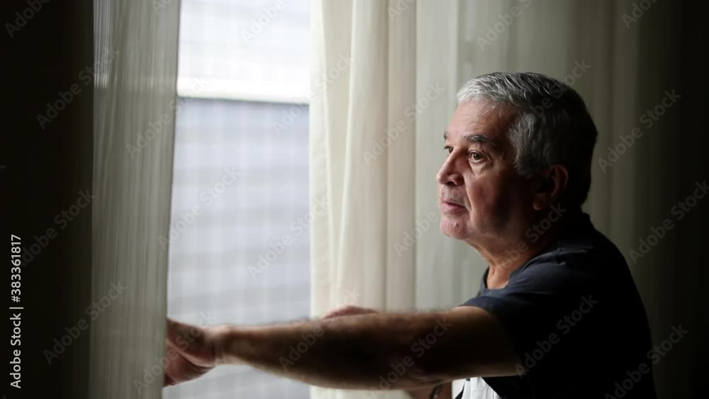 Suspicious older man spying outside through window blinds Suspicious older man spying outside through window blinds