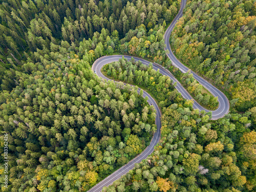 Winding road through the forest, from high mountain pass, in autumn season. Aerial view by drone. Romania