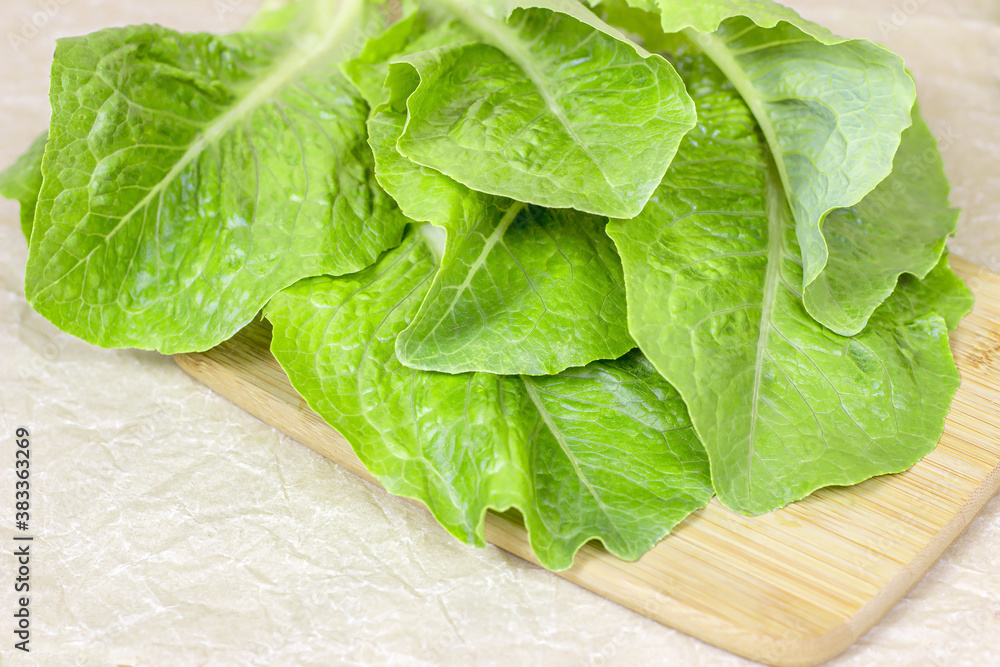 Fresh raw green romaine lettuce leaves for salad on light wooden textured background. Fresh raw green romaine lettuce leaves for salad on light wooden textured background.