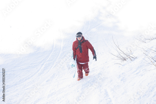 winter, leisure, sport and people concept - Snowboarder stands on backcountry slope and holds snowboard. Ski concept