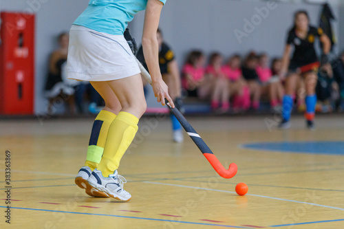 Young woman player in attack at indoor hockey match