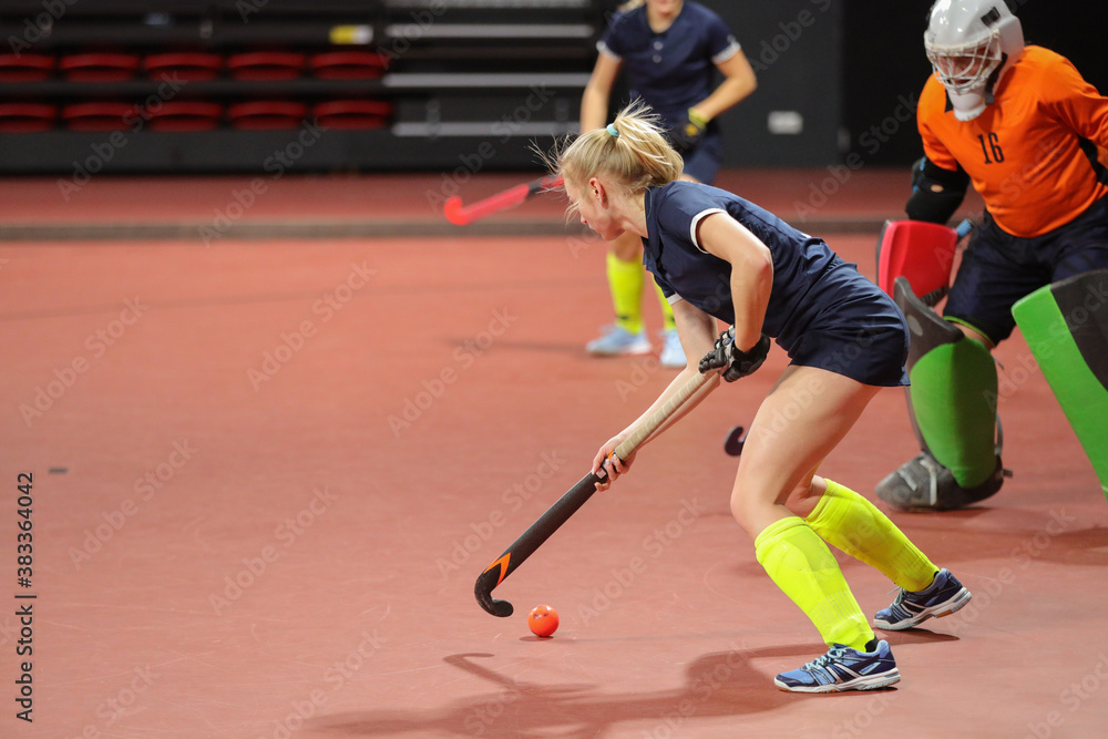 Young woman player in attack at indoor hockey match