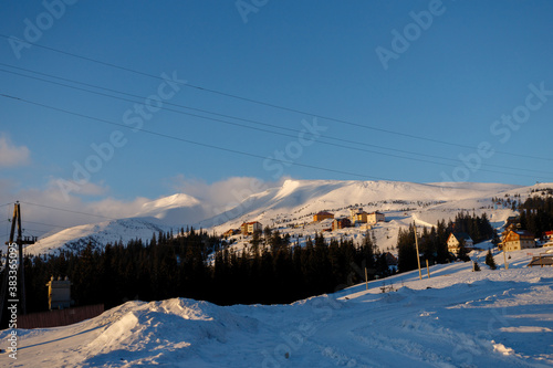 Ski piste and chair lift with snow covered trees on sunny day. Combloux ski area, French alps