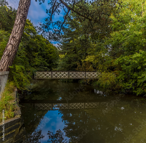 A view of a bridge and its reflection over the River Eye in New Park, Melton Mowbray, Leicestershire, UK in the summertime