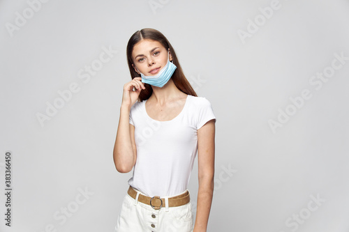 happy woman in medical mask holds her hand near her face and tilted her head 
