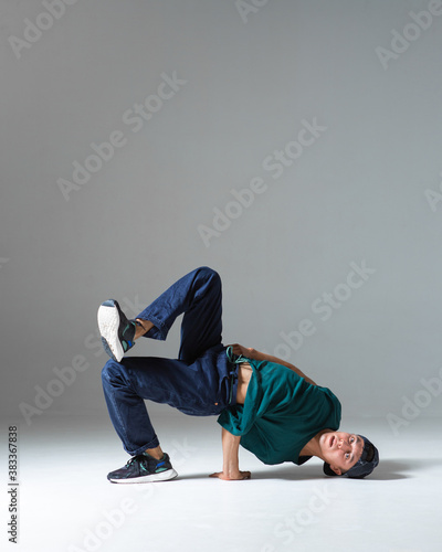 Cool b-boy dancing in studio isolated on gray background with copy space. Dancing school poster