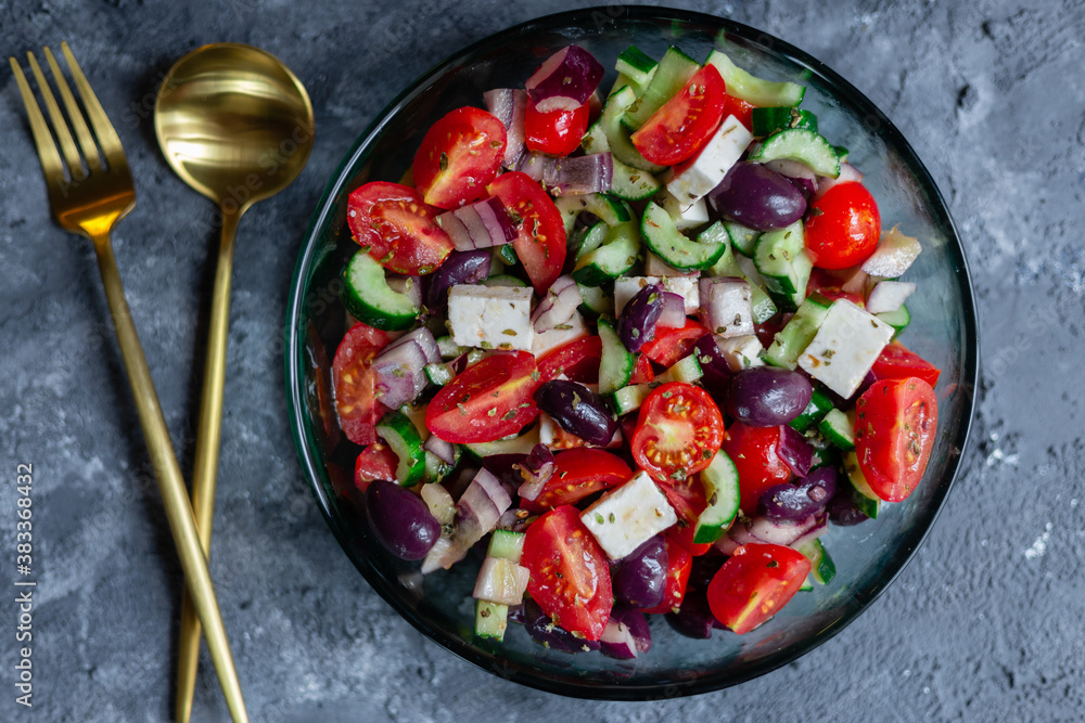 Greek salad on grey surface with golden silverware