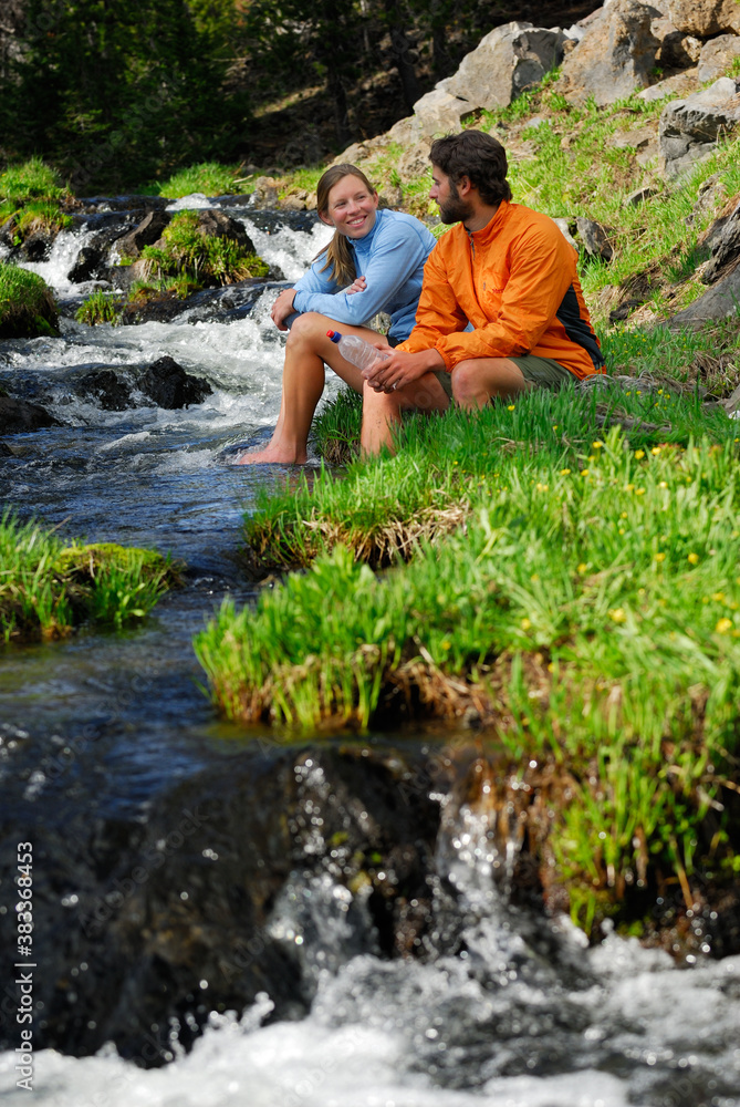 Naklejka premium Pair of Hikers relaxing with feet in a cold mountain stream