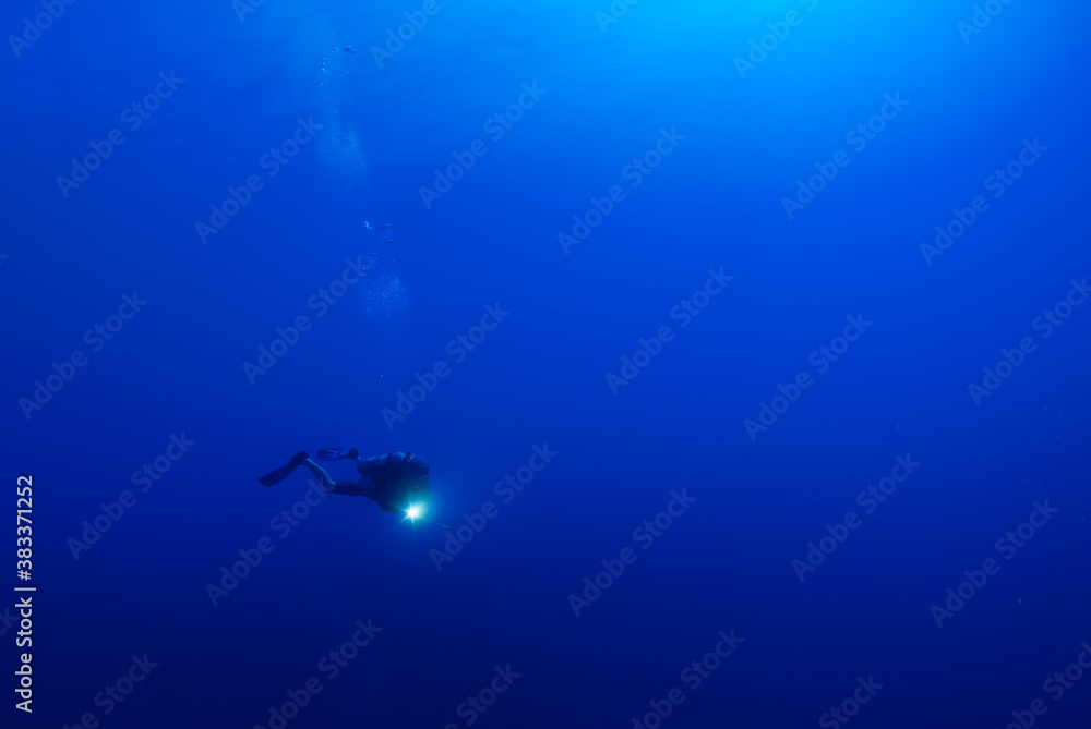 A scuba diver in the deep blue looking small against the might of the ocean