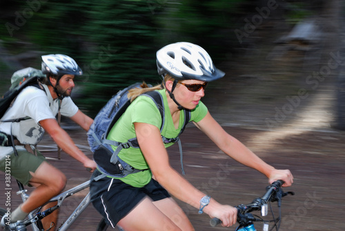 Male and female mountain bikers speeding along trail