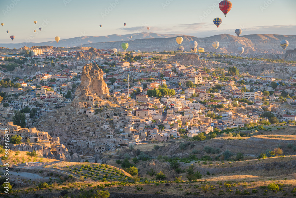 Bbaloons flying over Cappadocia landscape at sunrise with village