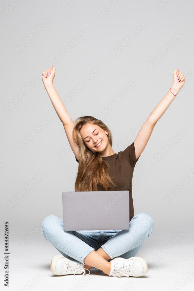 Young woman sitting on pufff with laptop with win gesture isolated on white background Young woman sitting on pufff with laptop with win gesture isolated on white background