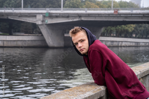 Obraz na płótnie sad lonely teenager in hoodie by the river w salonie