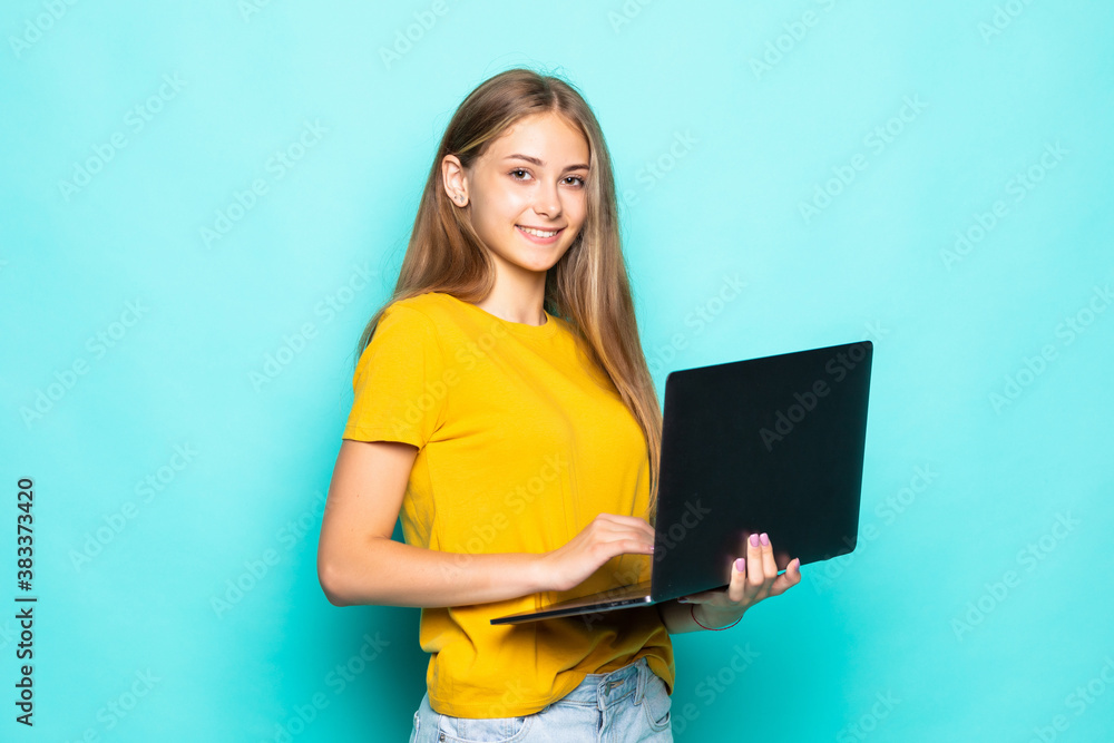 Young woman working on laptop posing isolated on turquoise background Young woman working on laptop posing isolated on turquoise background