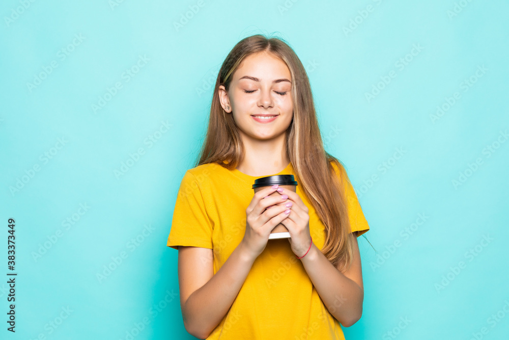 Happy woman smiling and drinking coffee isolated over turquoise background