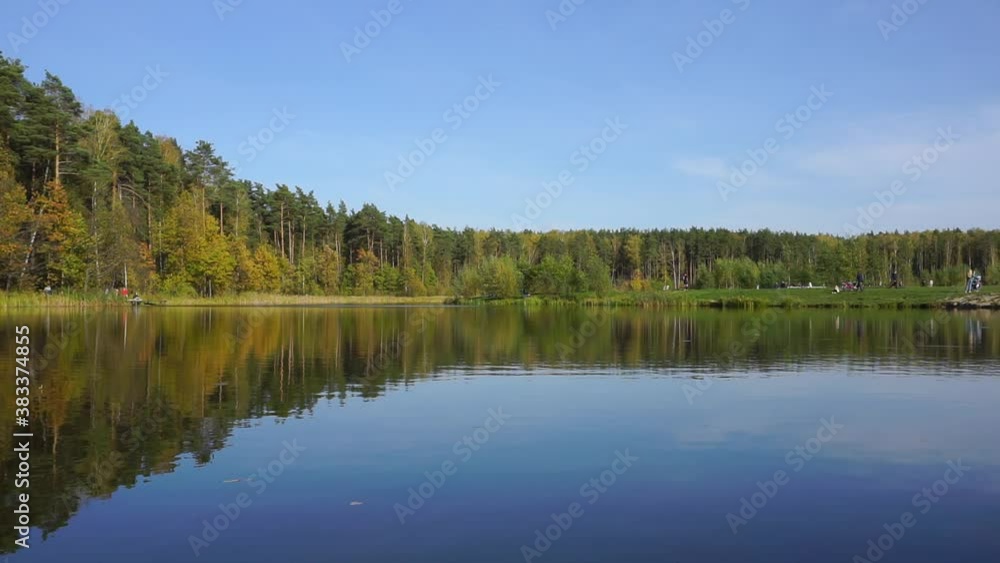 Lake in the forest with calm water. In the background there is a forest, trees are reflected in calm water. Lake in the forest with calm water. In the background there is a forest, trees are reflected in calm water.