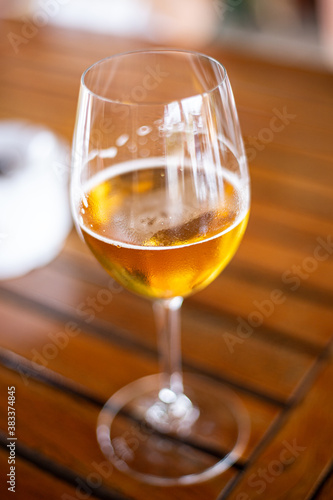Cold blond beer served on a wineglass close up still isolated on a wooden table